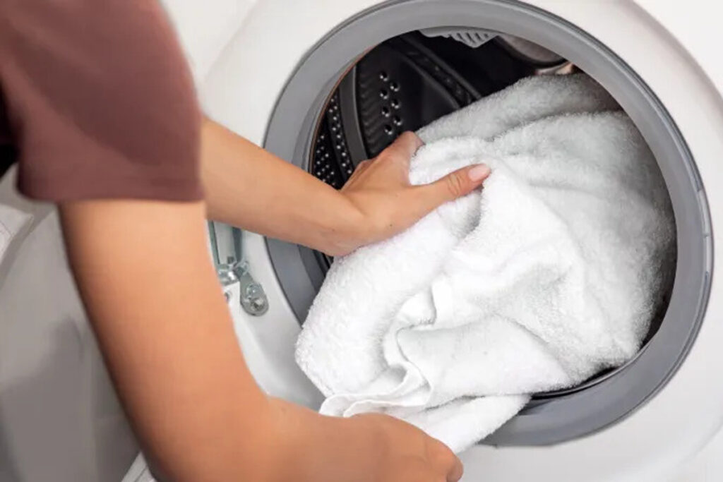 Imagem ilustrativa com o título "Secadora de Roupa Gasta Muita Energia? Descubra o Consumo Real", mostrando uma secadora em funcionamento e elementos que remetem ao consumo elétrico.