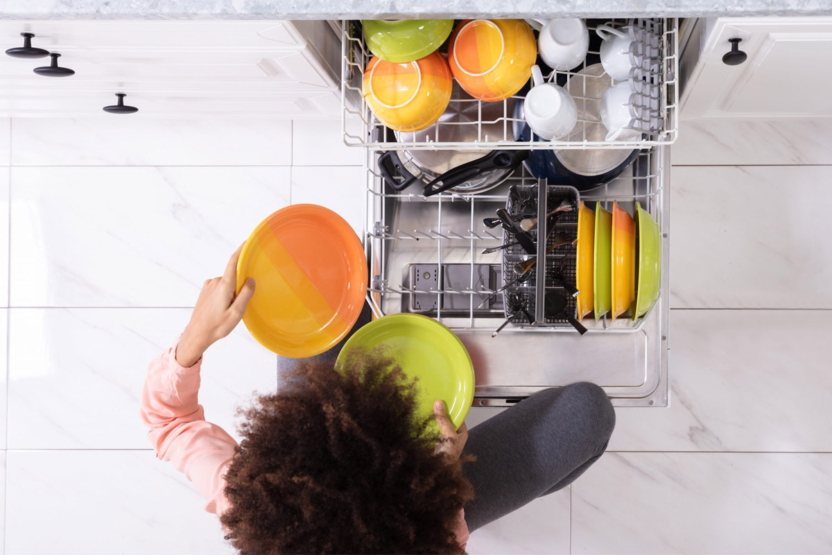 Família pequena ou casal com filhos na cozinha, com destaque para uma máquina de lavar louças de tamanho médio (8 a 10 serviços) integrada ao ambiente.